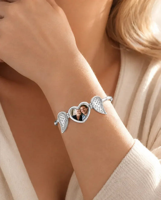 Woman wearing silver angel wing heart photo bangle in a garden