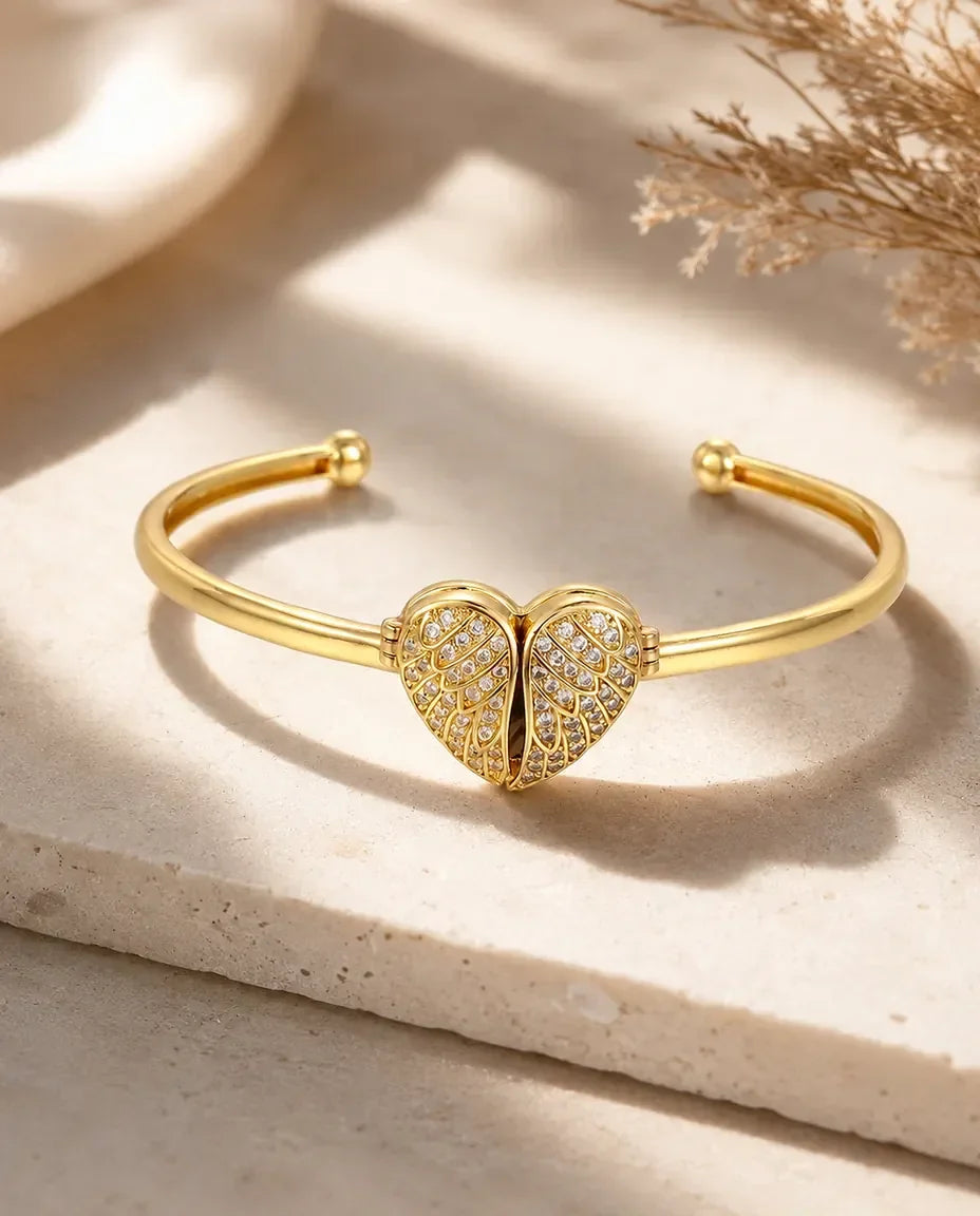 Gold cuff bangle with pave winged heart closed, flat lay