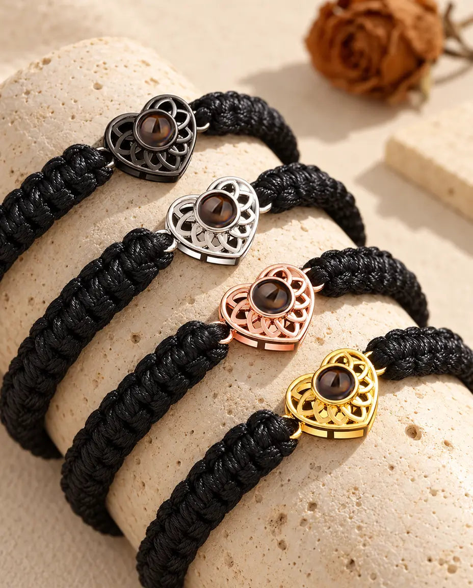 Four black braided cord bracelets showing every charm color draped over travertine