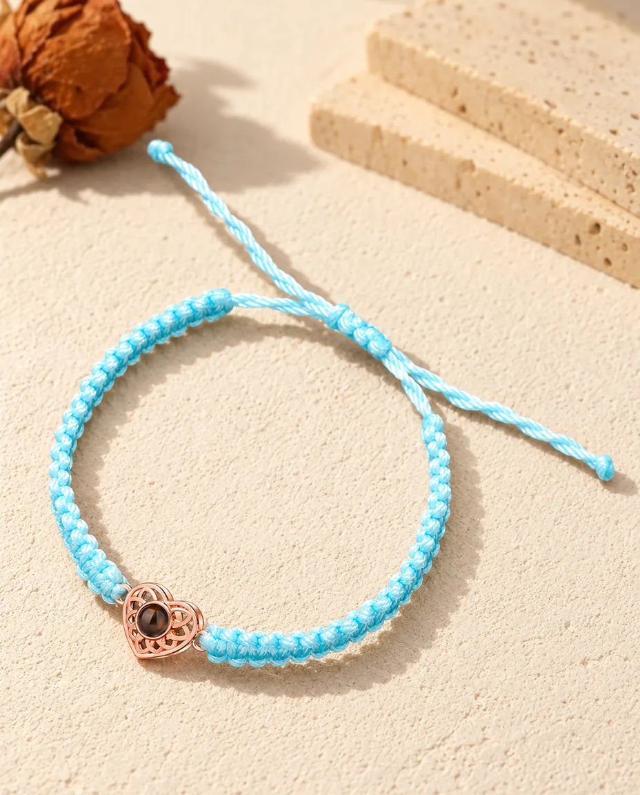 Rose gold tone heart charm on a light blue braided cord with adjustable sliding knot