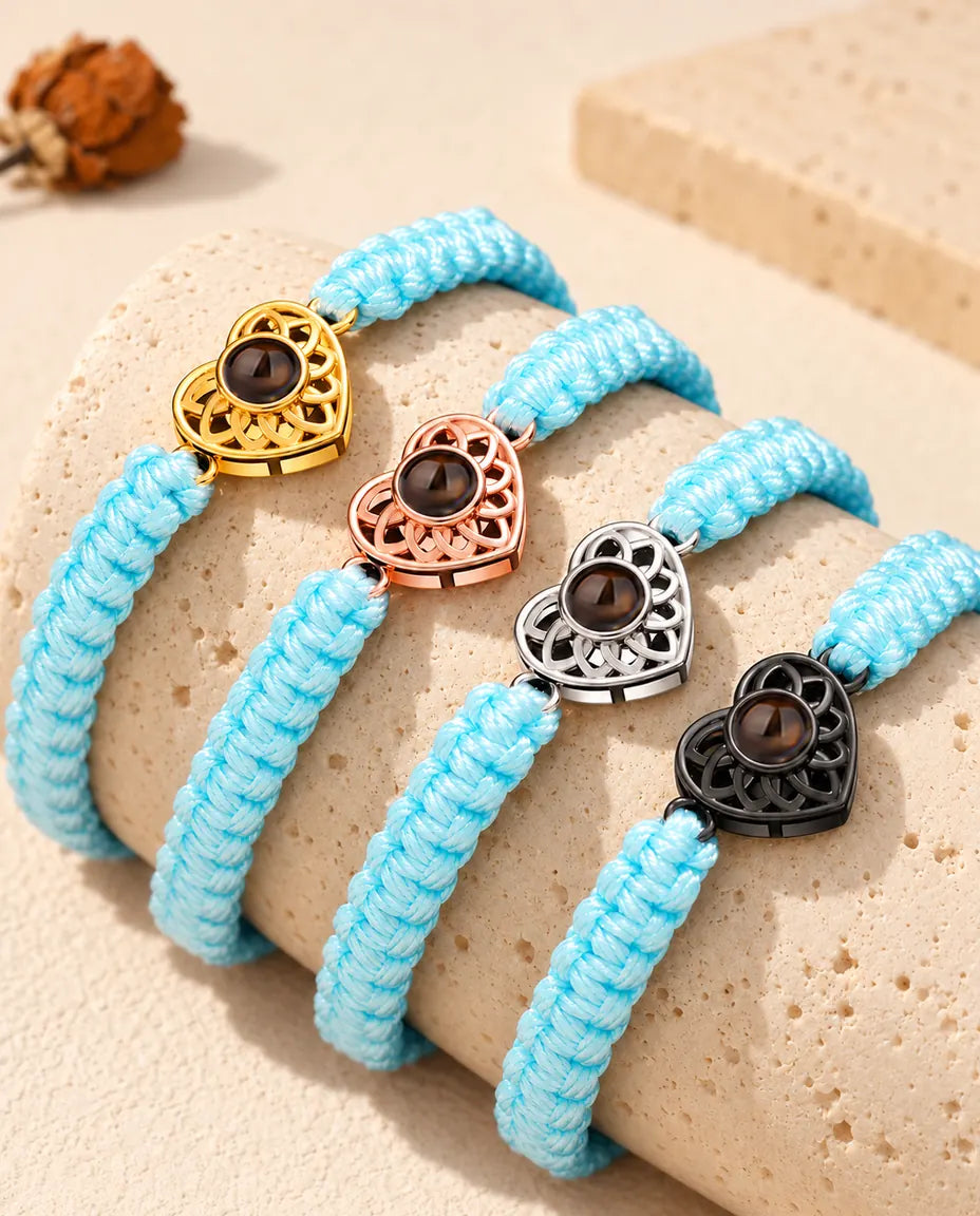 Light blue braided cord projection bracelets lined up on a travertine block in each charm color