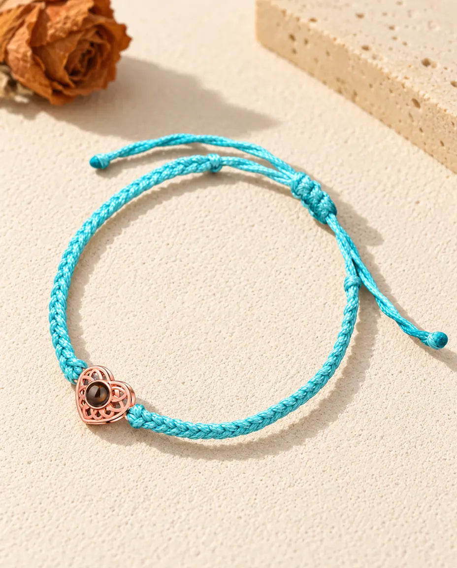 Rose gold tone heart charm on a blue thin braided cord with adjustable sliding knot