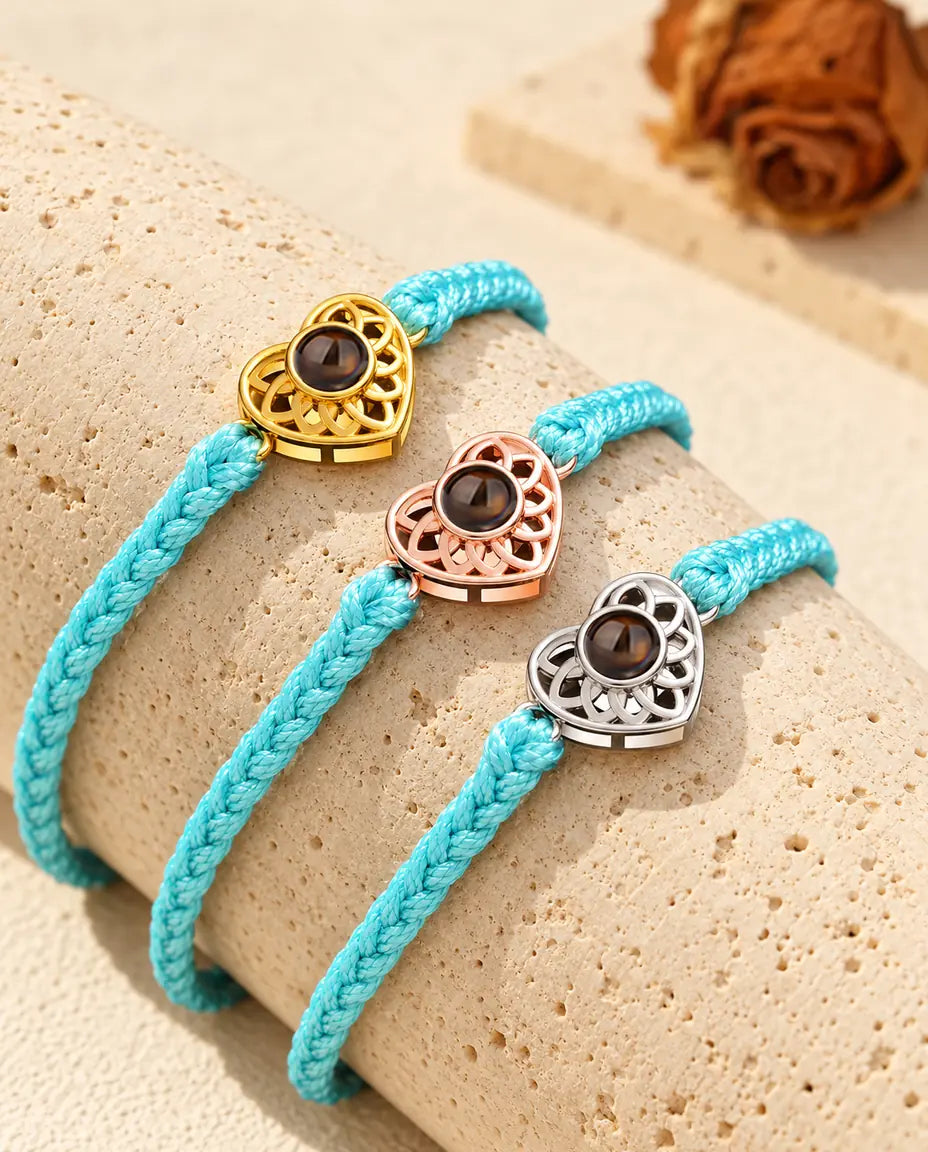 Blue thin braided cord projection bracelets with gold tone, rose gold tone and silver tone heart charms on travertine