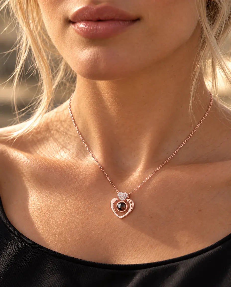 Woman in a black top wearing the rose gold tone open heart projection necklace