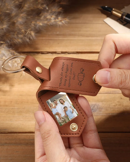 Hands holding an open brown faux leather photo keychain with two family photos