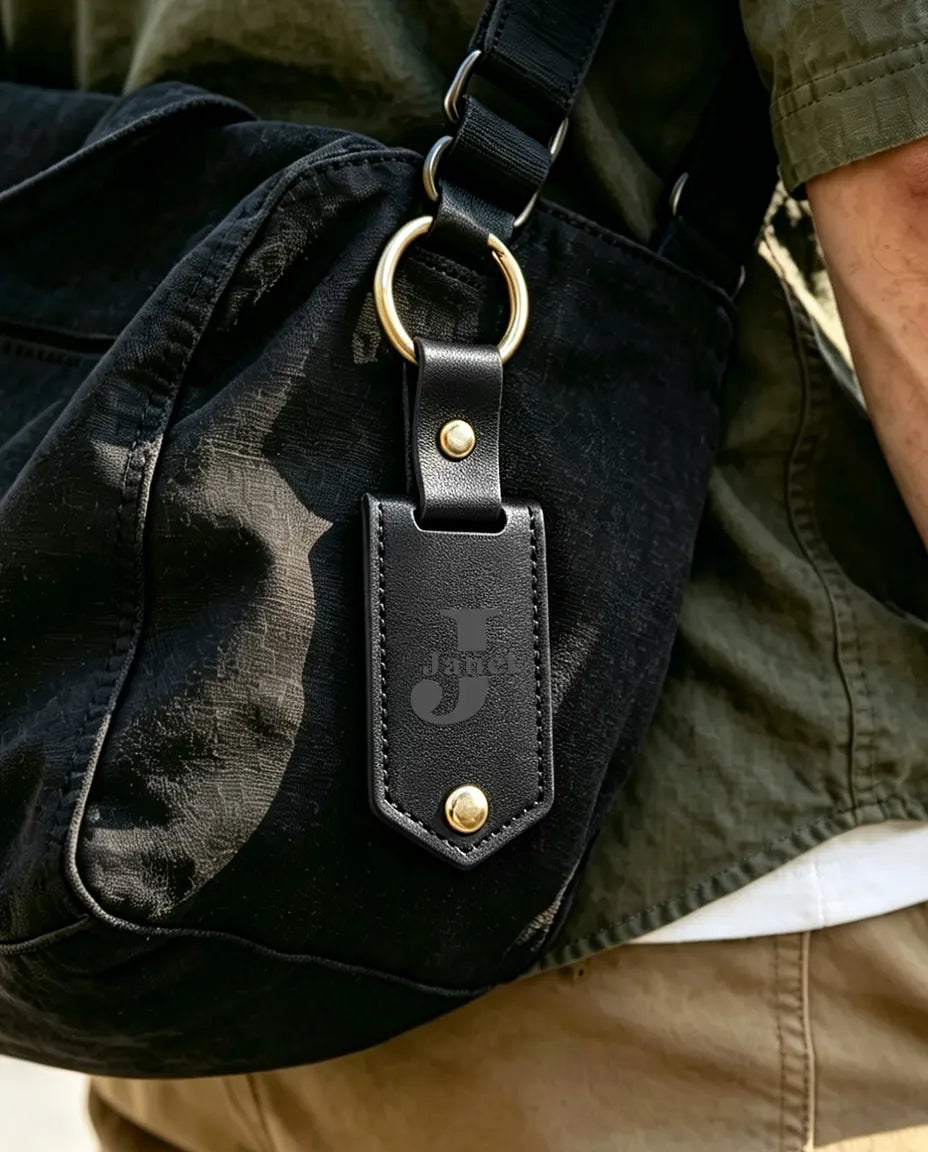 Black engraved faux leather photo keychain clipped to a bag