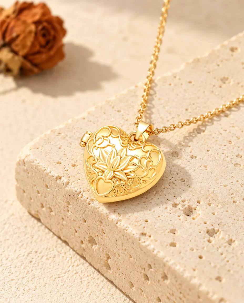 Gold tone lotus flower heart photo locket necklace resting on a travertine block