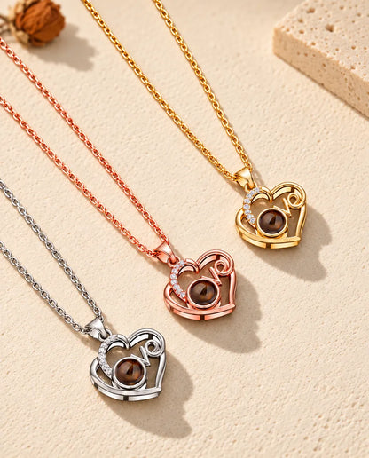 Silver tone, rose gold tone and gold tone Love heart projection necklaces laid diagonally on plaster
