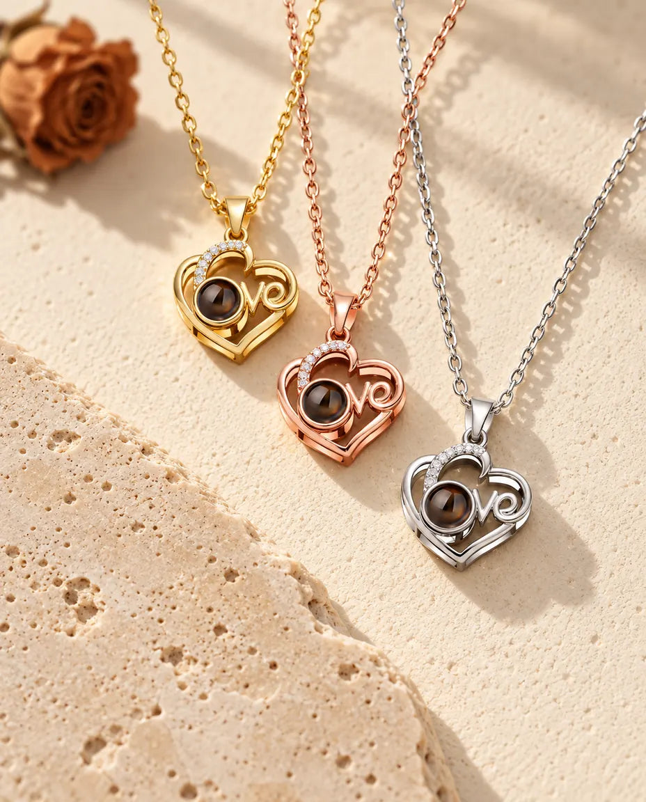 Gold tone, rose gold tone and silver tone Love heart projection pendants stacked beside a travertine slab