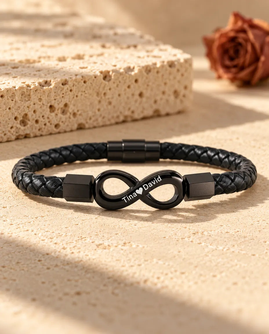 Personalized men's infinity bracelet in black on a braided faux leather cord, engraved with two names and a heart