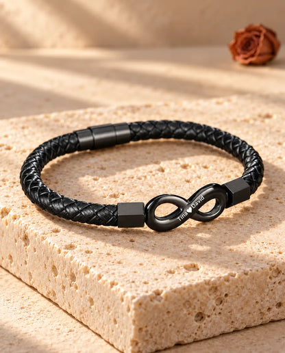 Three-quarter view of the men's engraved infinity bracelet with magnetic barrel clasp on travertine