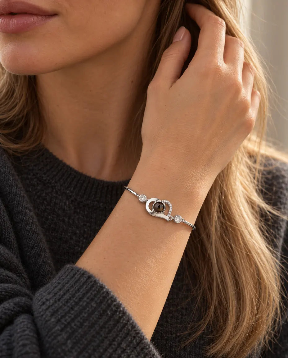 Woman with her hand in her hair, wearing the silver tone open heart projection bracelet