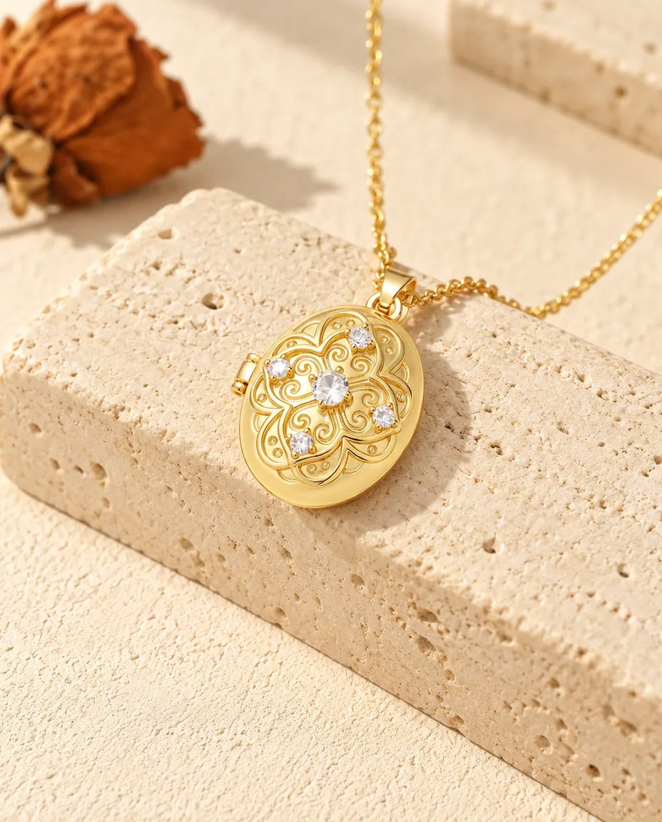 Gold tone oval filigree locket necklace draped over a travertine block