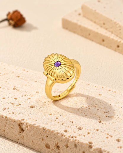 Closed oval locket ring standing on a travertine block