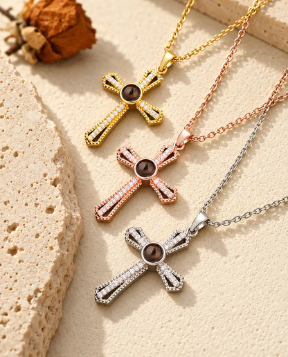 Gold tone, rose gold tone and silver tone cross projection necklaces stacked beside a travertine slab