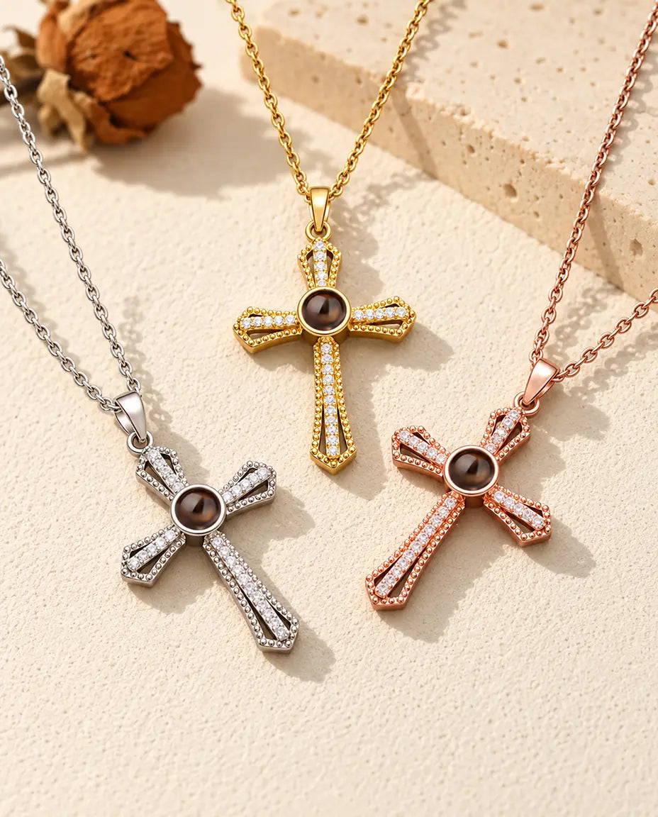 Three colors of the pave cross photo necklace laid out on cream plaster