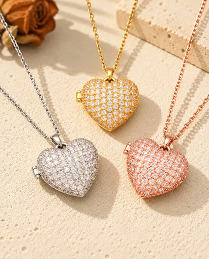Three colors of the pave heart photo locket necklace arranged on plaster