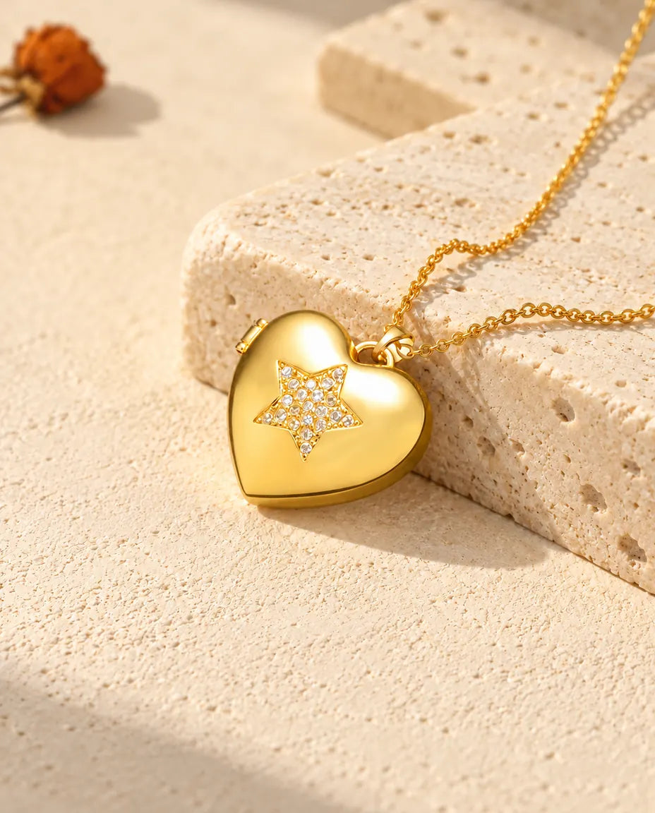 Gold tone pave star heart photo locket necklace resting on a travertine block