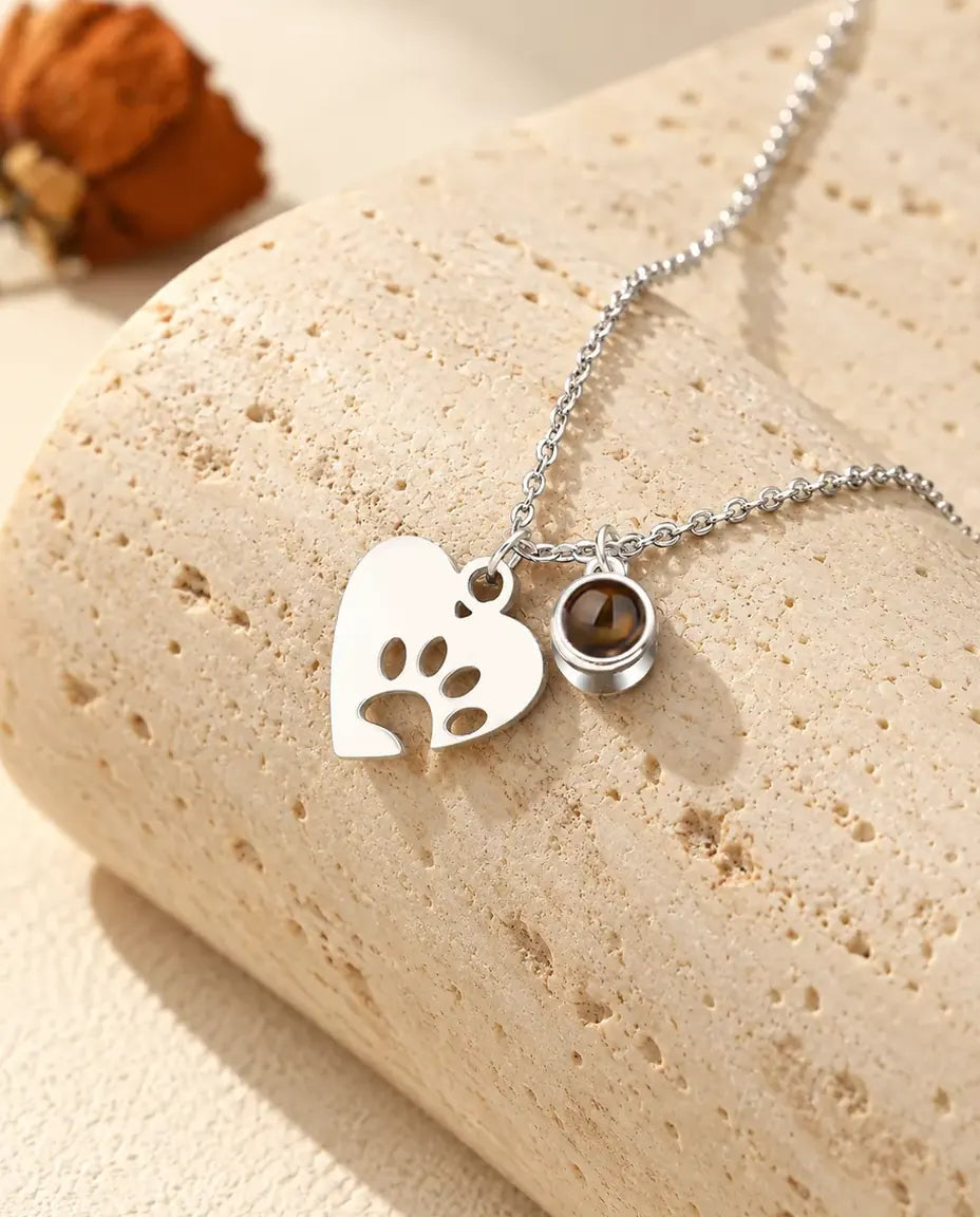 Personalized pet photo projection necklace in silver tone with a paw print heart and a tiny projection stone charm