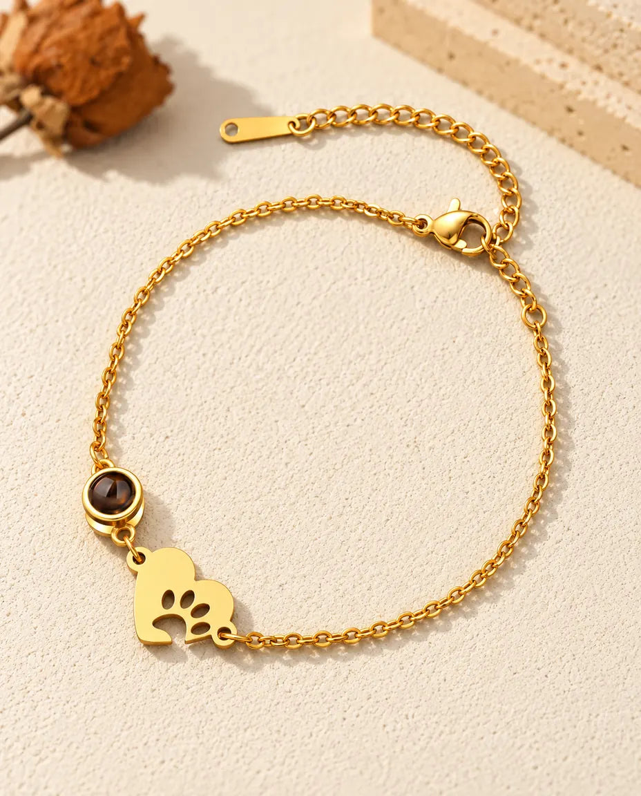 Gold tone pet memorial bracelet with a paw print heart tag and extender chain