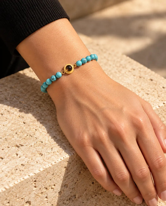 Woman wearing the blue marbled bead bracelet with a gold tone projection charm on her wrist