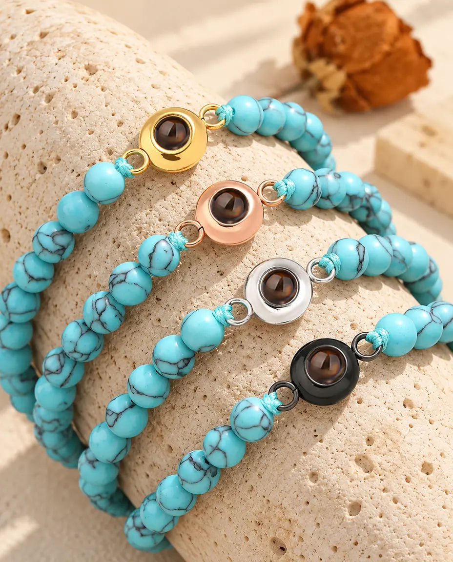 Four blue marbled bead projection bracelets in gold tone, rose gold tone, silver tone and black on travertine