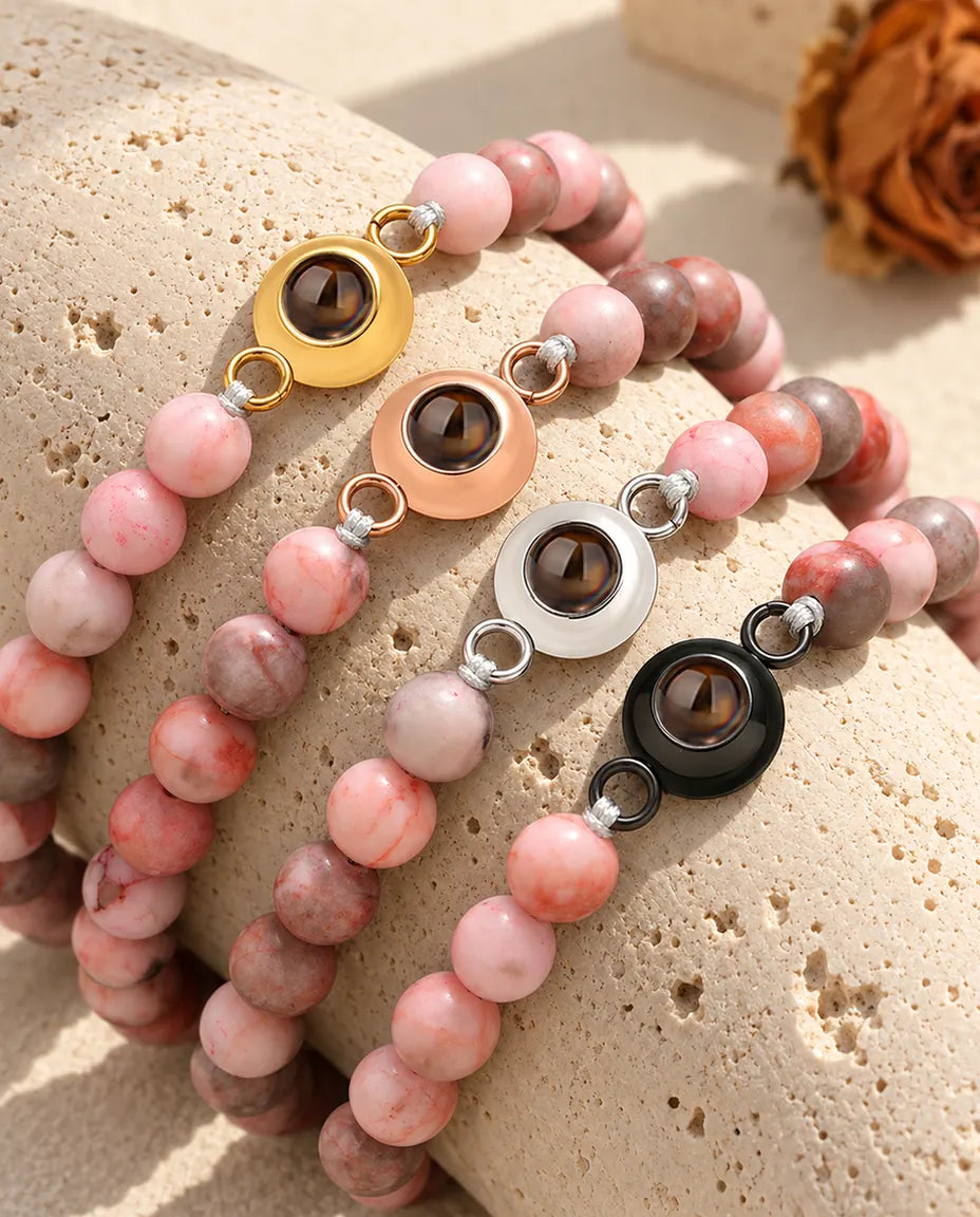 Pink speckled bead projection bracelets in each charm color on travertine