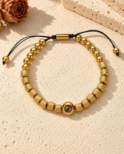 Top view of the gold tone photo projection bead bracelet with its sliding cord