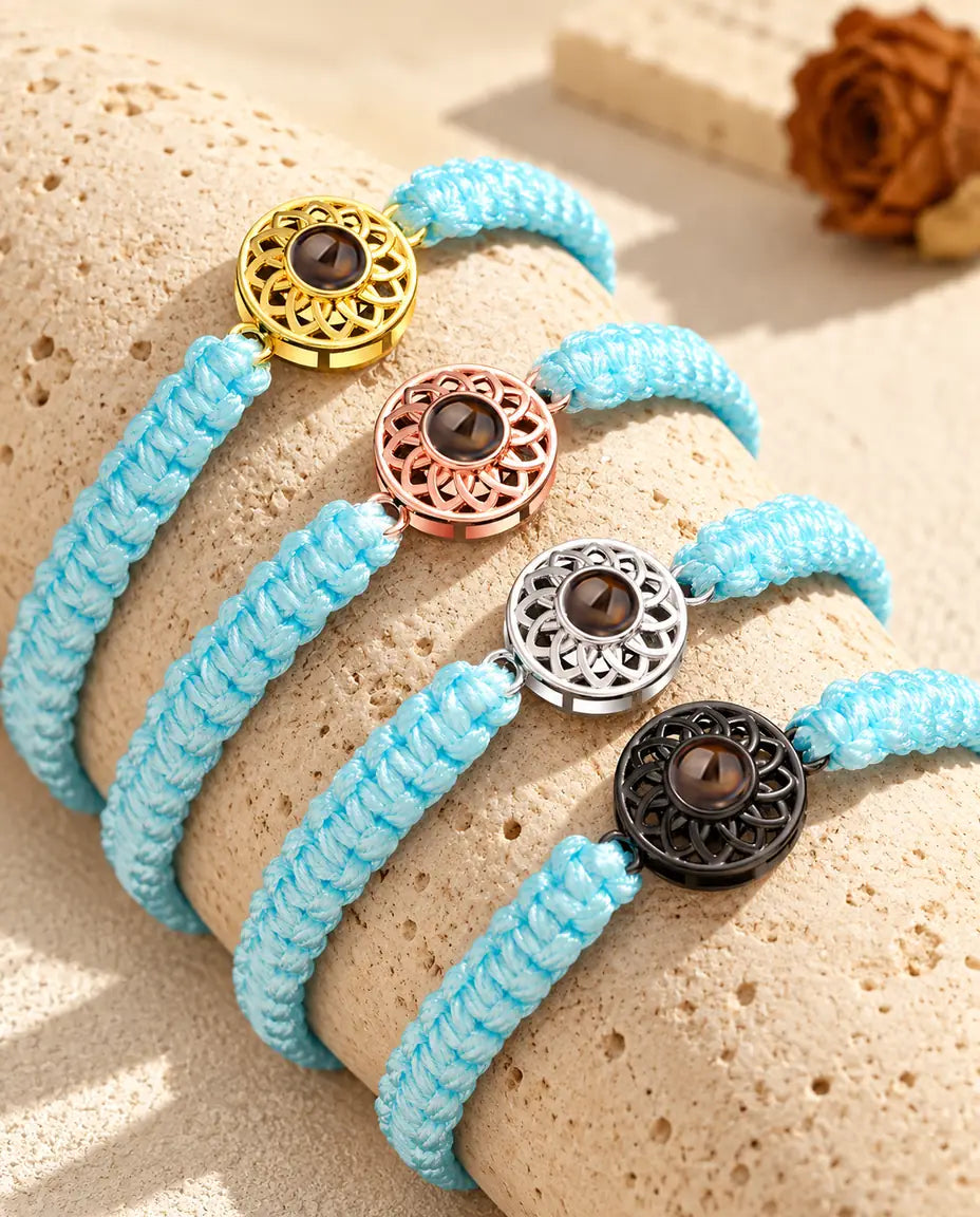 Light blue braided cord projection bracelets lined up on a travertine block in each charm color