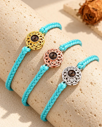 Blue thin braided cord projection bracelets with gold tone, rose gold tone and silver tone round charms on travertine