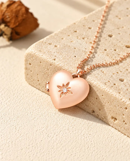 Rose gold tone satin flower heart photo locket necklace on travertine in warm sunlight