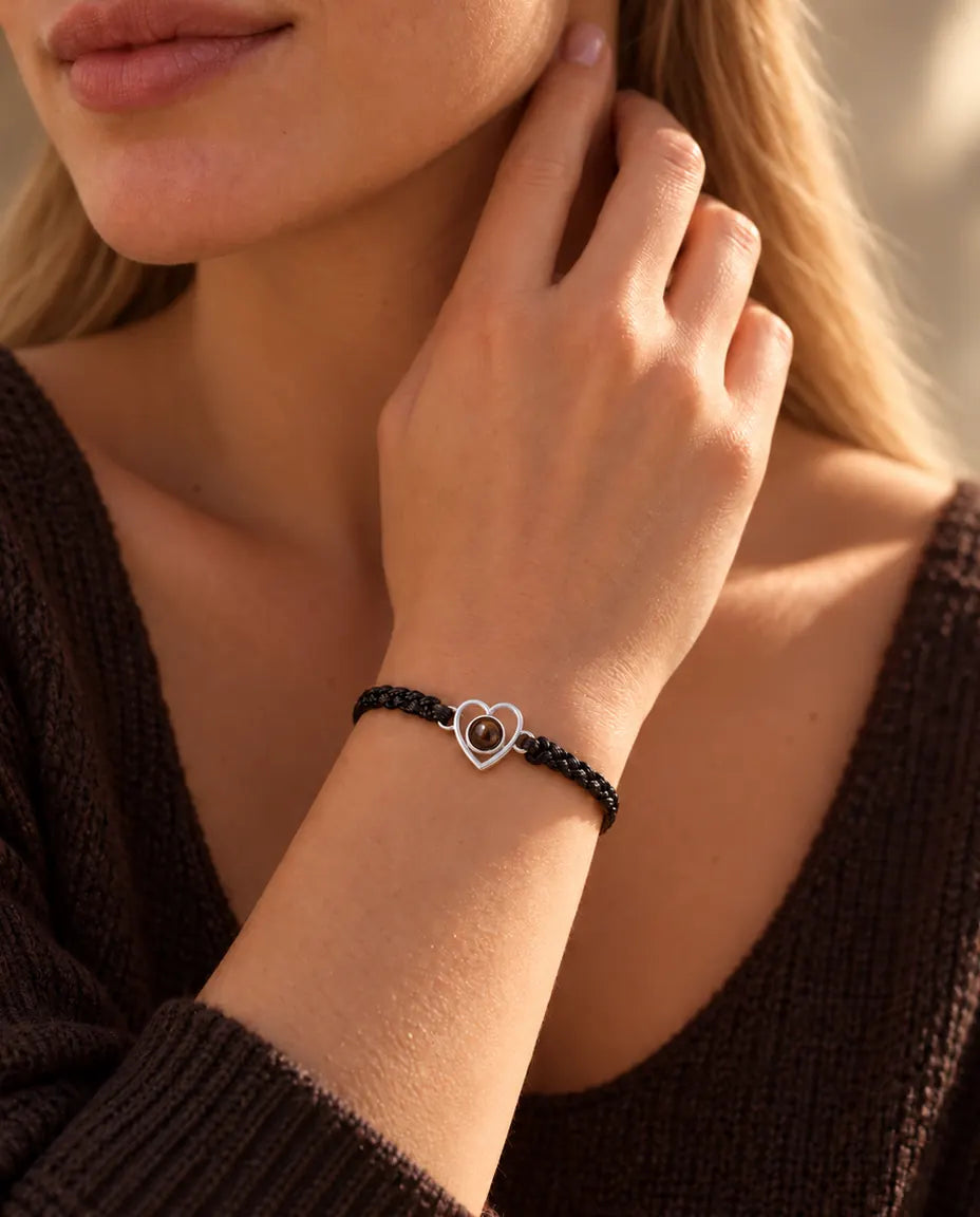 Woman with her fingertips at the side of her neck wearing the silver open heart bracelet on a black cord