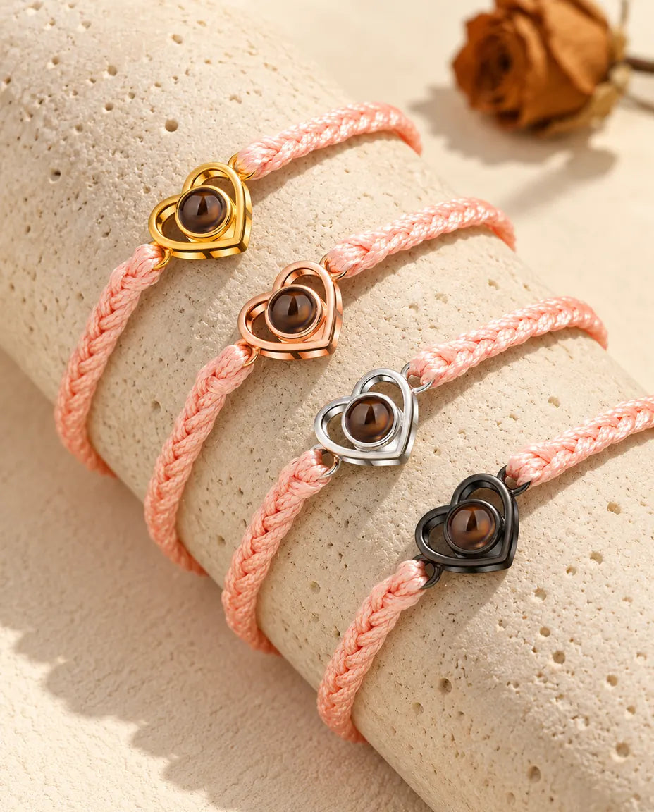 Pink braided cord open heart bracelets showing every charm color draped over travertine