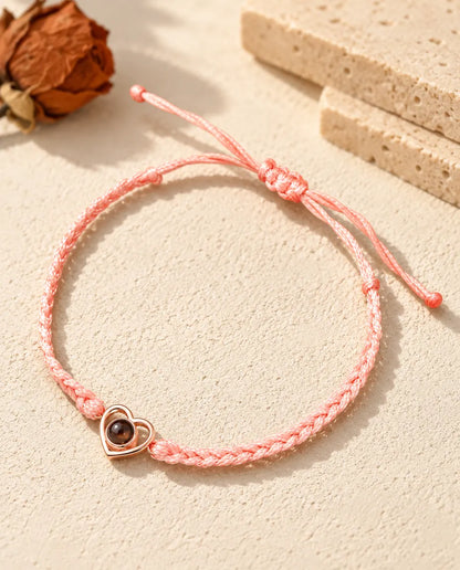 Rose gold tone open heart charm on a pink braided cord with adjustable sliding knot