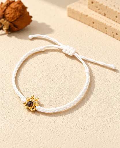 White braided cord photo projection bracelet with a gold tone paw charm and sliding knot