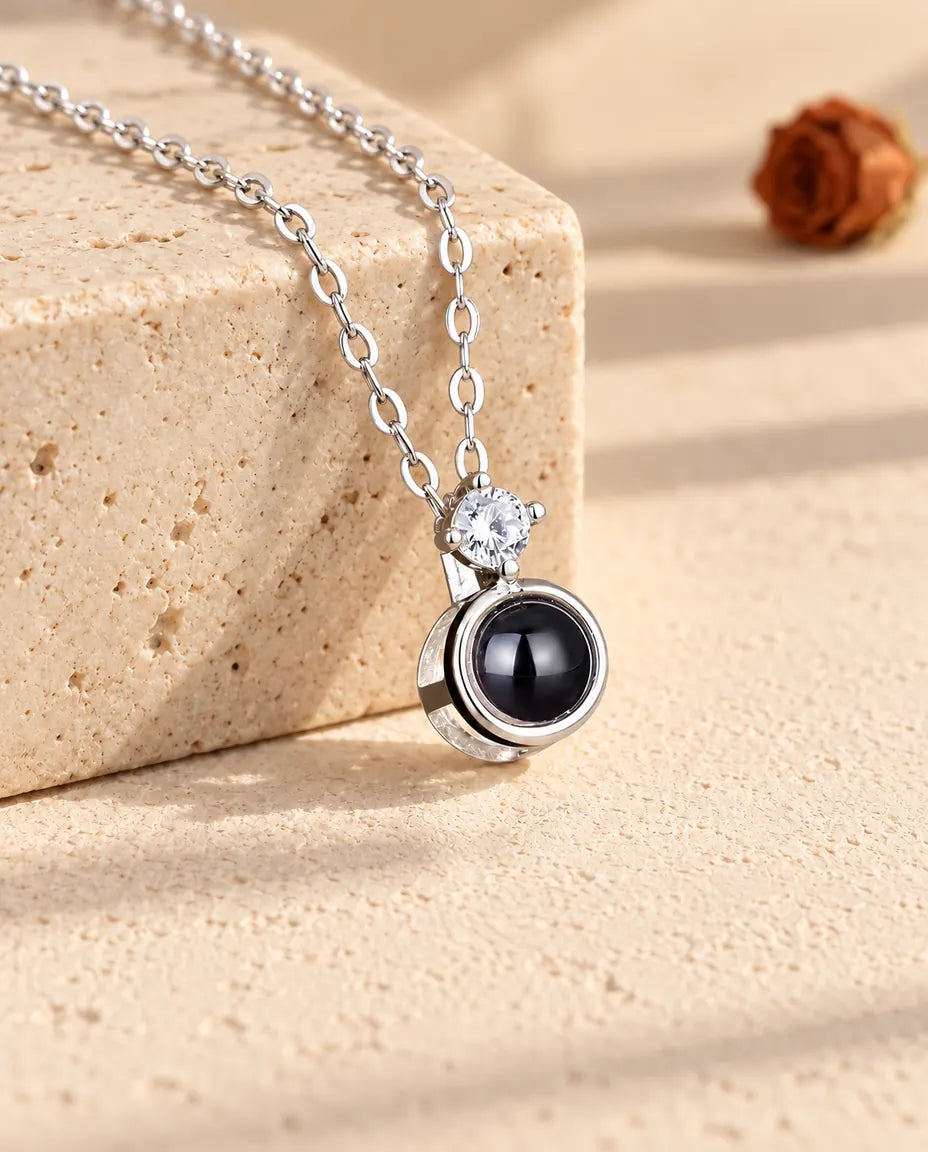 Silver tone solitaire projection necklace draped over a travertine block