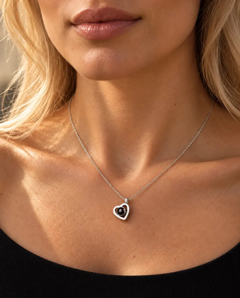 Woman in a black knit top wearing the tiny sterling silver double heart projection necklace
