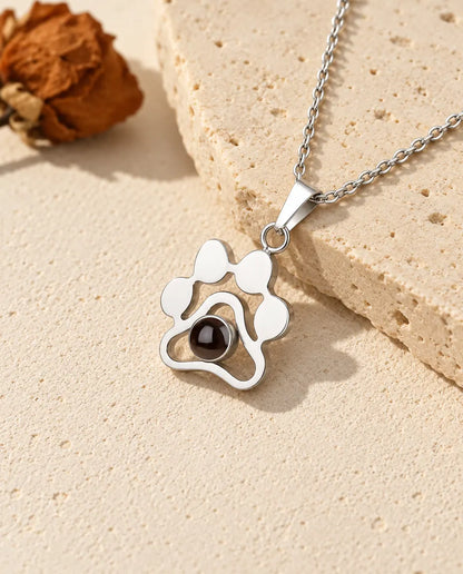 Personalized sterling silver paw print photo projection necklace on a travertine slab