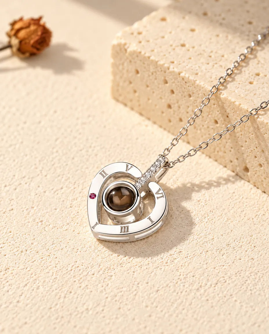Personalized 925 sterling silver Roman numeral heart photo projection necklace on cream plaster beside travertine