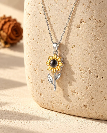 Sunflower photo projection necklace hanging on a rounded travertine block