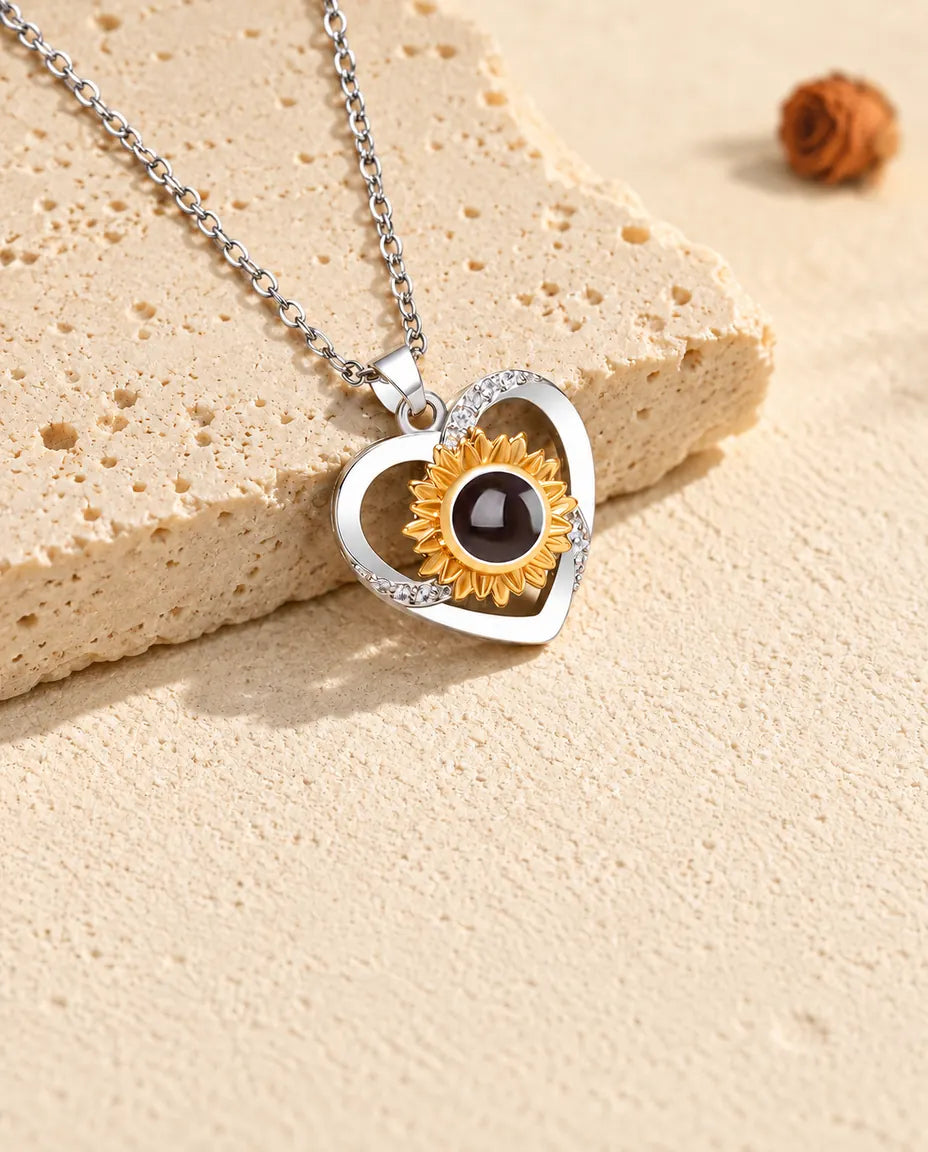 Sunflower heart projection necklace tilted beside a travertine slab