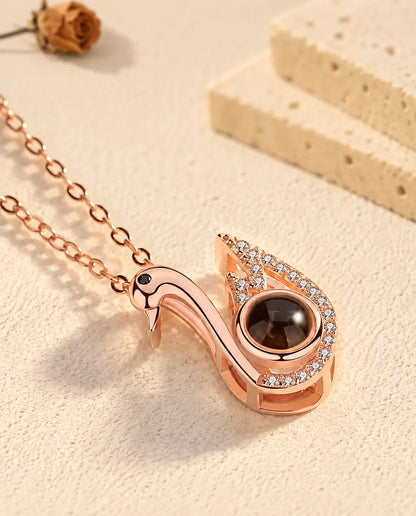 Rose gold tone swan projection pendant tilted on cream plaster