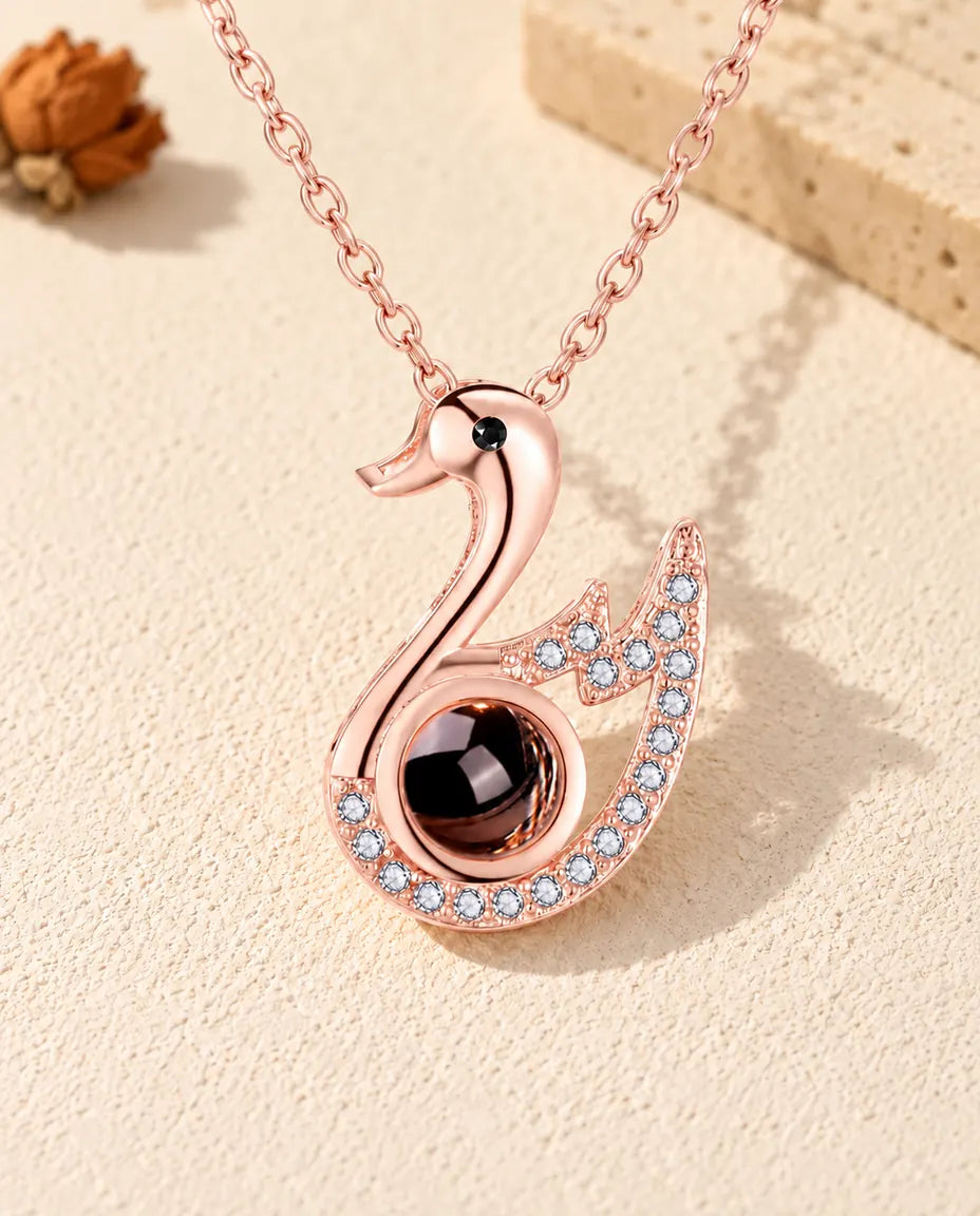 Front view of the rose gold tone swan photo projection necklace