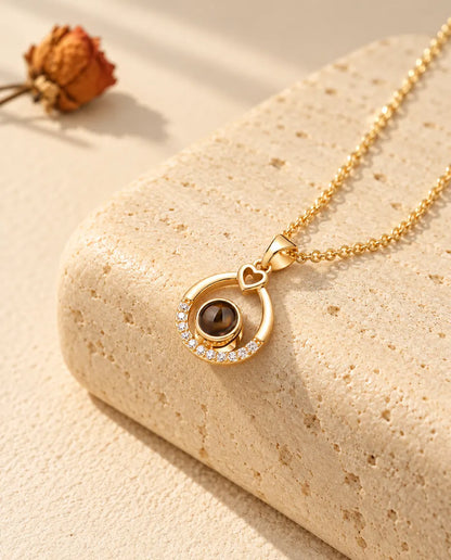 Personalized gold tone teardrop photo projection necklace with a little heart on travertine
