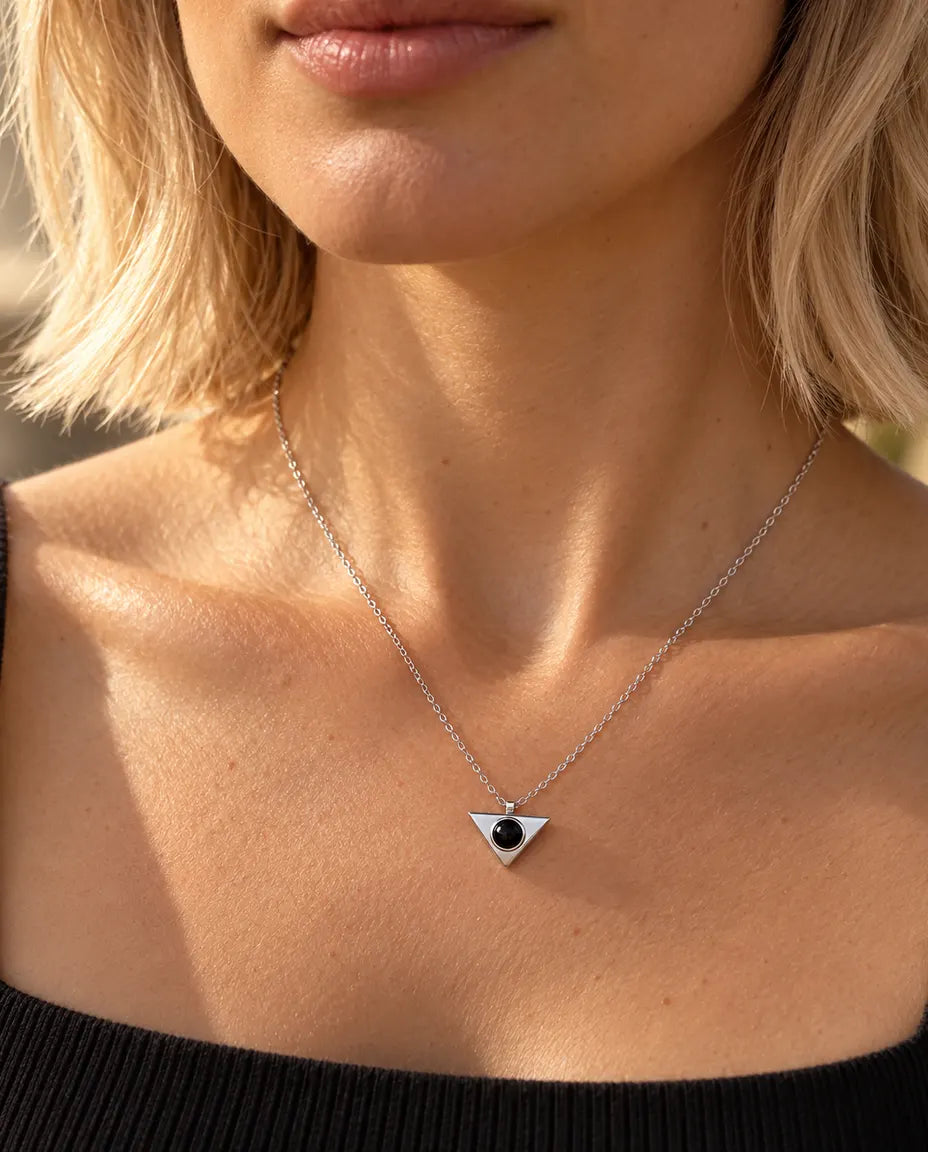 Woman in a black top wearing the minimalist silver tone triangle projection necklace