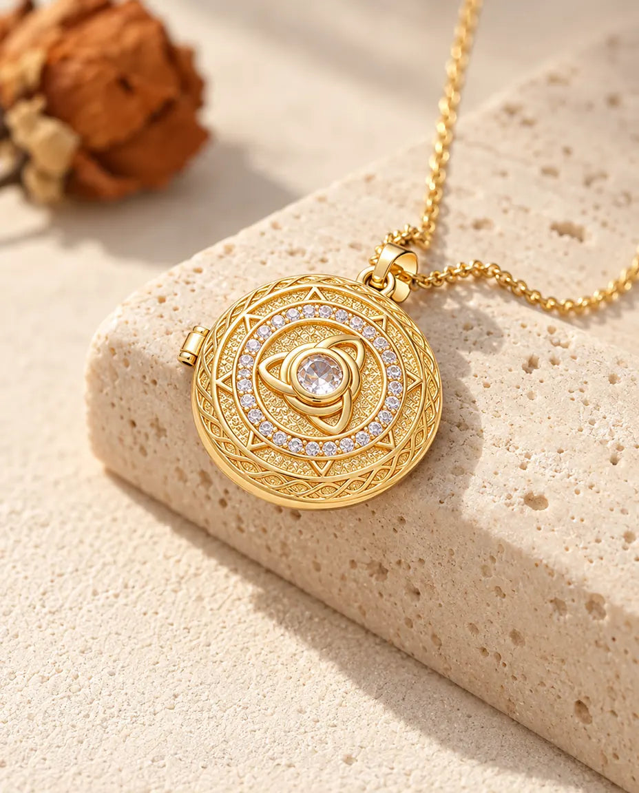Gold tone round trinity knot locket necklace with a center stone draped over a travertine block