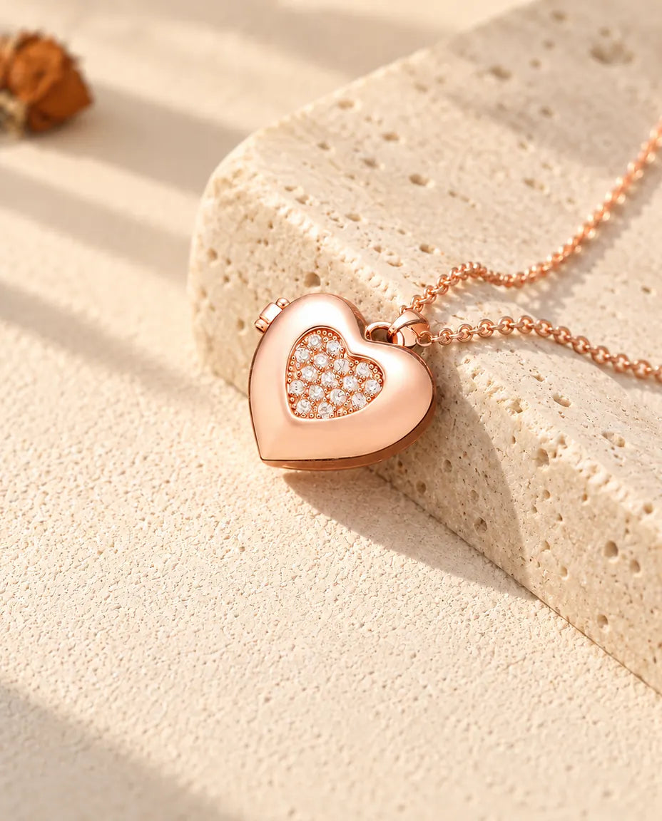 Rose gold tone two-tone pave heart photo locket necklace on travertine in warm sunlight