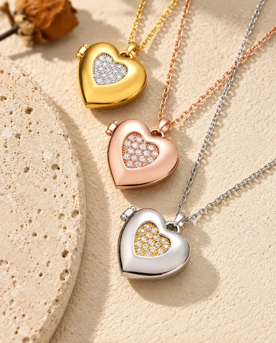 Gold tone, rose gold tone and silver tone two-tone pave heart photo lockets stacked beside a travertine slab