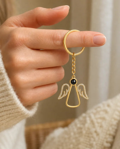 Woman holding the gold angel photo projection keychain by its key ring