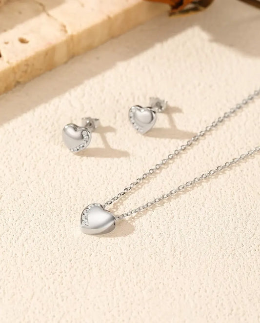 Heart Jewelry Set in 925 Sterling Silver - necklace and earrings laid together on a cream textured surface